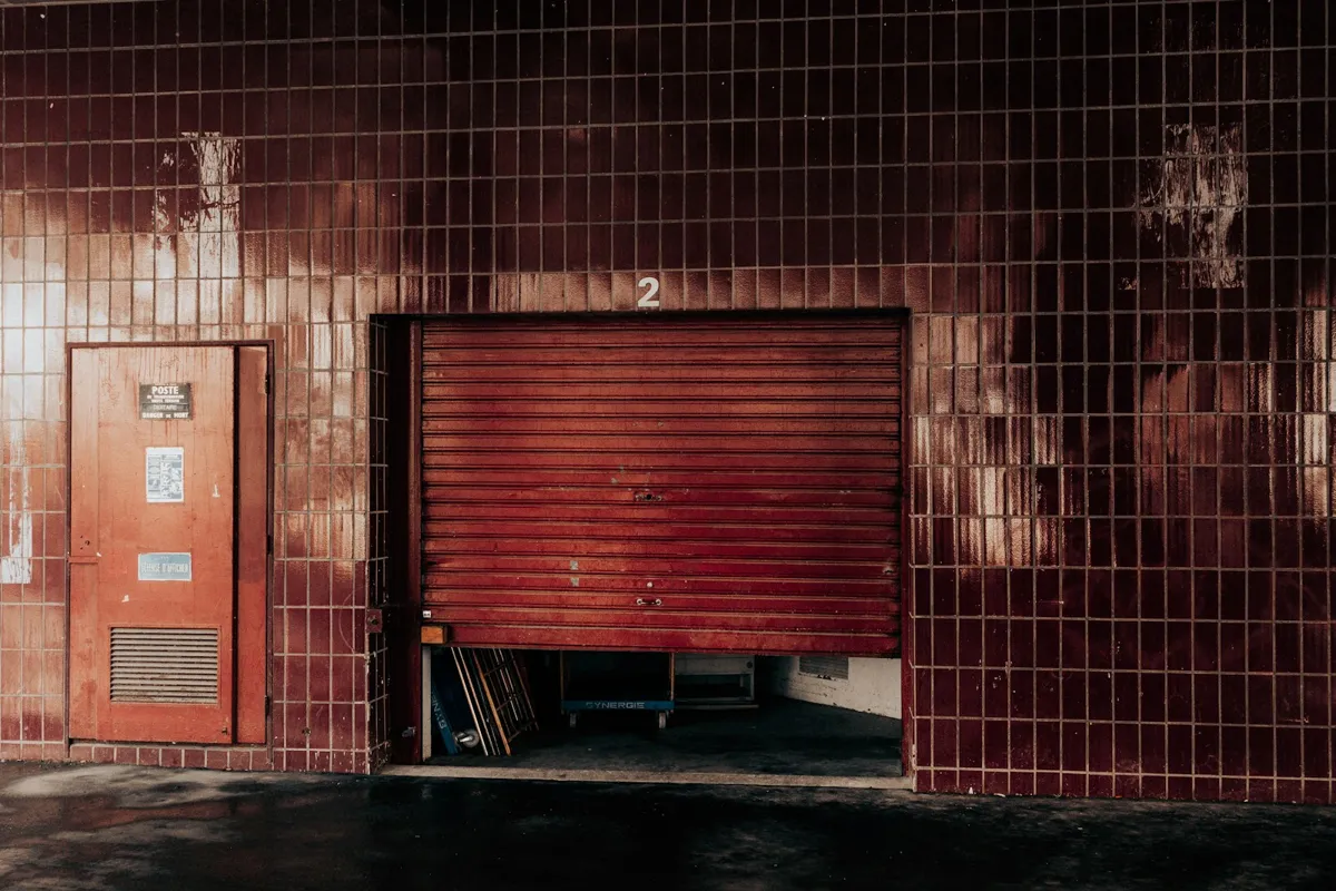 Red roll-up door partly open in a tiled wall